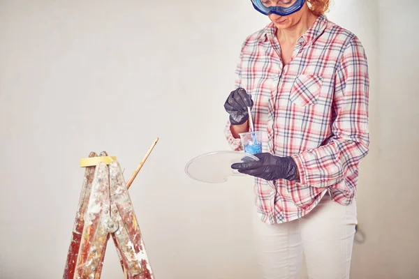 Mujer trabajadora enyesando / pintando paredes dentro de la casa . — Foto de Stock