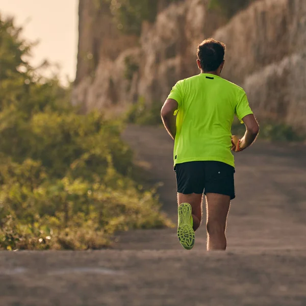 Hombre corriendo en una cuesta abajo / cuesta arriba en el camino de montaña suburbio . — Foto de Stock