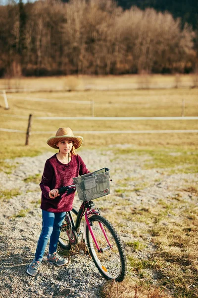 Bonito menina de dez anos andando de bicicleta no campo . — Fotografia de Stock