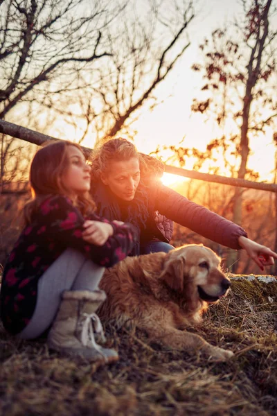 Mãe e filha com um labrador dourado no por do sol / nascer do sol t — Fotografia de Stock