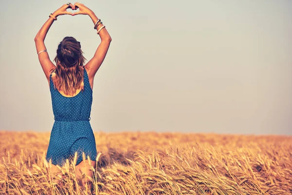 Girl holding heart-shape symbol for love in a wheat field. — Stock Photo, Image