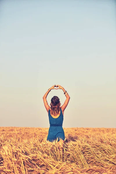 Дівчина тримає символ форми серця для кохання в пшеничному полі . — стокове фото