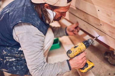 Erkek marangoz antika bir atölyede eski ahşap üzerinde çalışıyor..