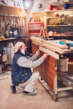 Erkek marangoz antika bir atölyede eski ahşap üzerinde çalışıyor..