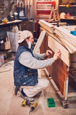 Erkek marangoz antika bir atölyede eski ahşap üzerinde çalışıyor..
