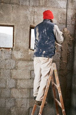 Gerçek inşaat işçisi yeni evin içinde bir duvar yapma.