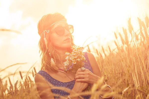 Woman with bouquet of flowers in a wheat field. — Stock Photo, Image