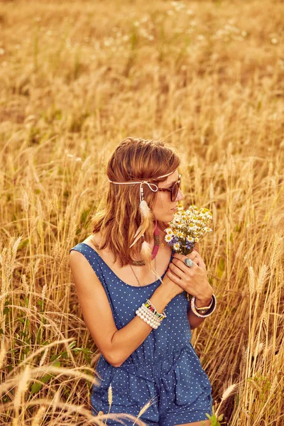 Woman with bouquet of flowers in a wheat field. — Stock Photo, Image