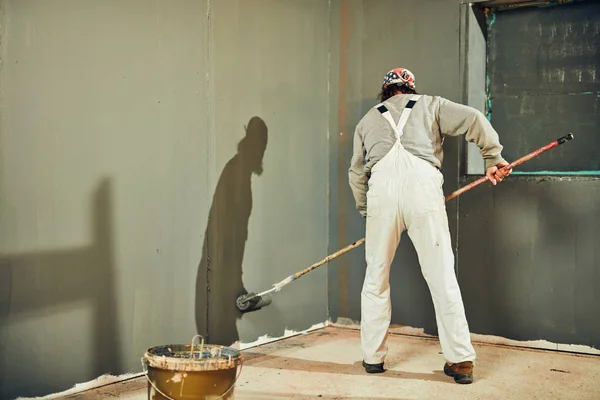 Painter painting walls with a extender roller indoors. — Stock Photo, Image