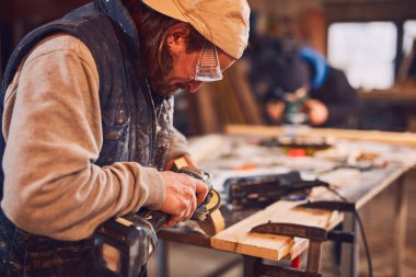 Erkek marangoz antika bir atölyede eski ahşap üzerinde çalışıyor..
