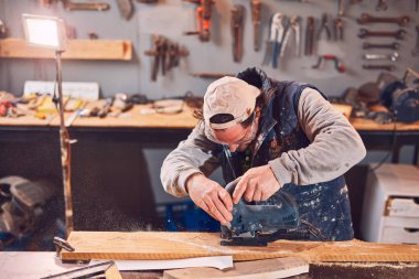 Erkek marangoz antika bir atölyede eski ahşap üzerinde çalışıyor..