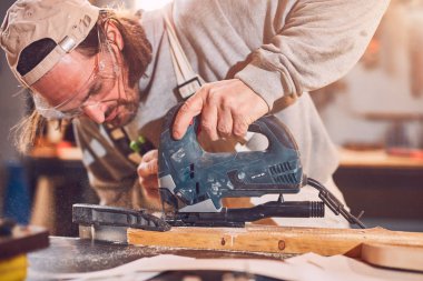 Erkek marangoz antika bir atölyede eski ahşap üzerinde çalışıyor..