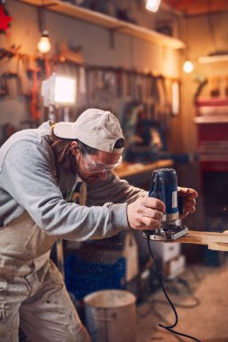 Erkek marangoz antika bir atölyede eski ahşap üzerinde çalışıyor..