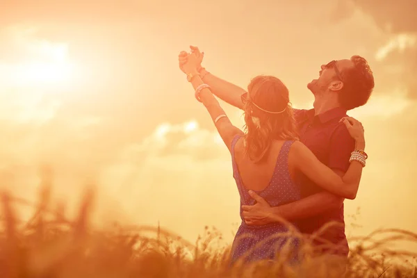 Casal ao pôr do sol / nascer do sol em um campo de trigo . — Fotografia de Stock