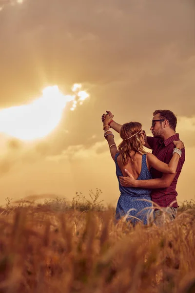 Pareja en la puesta del sol / salida del sol en un campo de trigo . —  Fotos de Stock