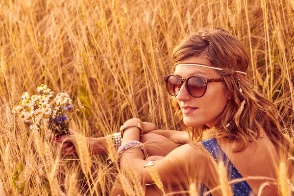 Woman with bouquet of flowers in a wheat field. — Stock Photo, Image