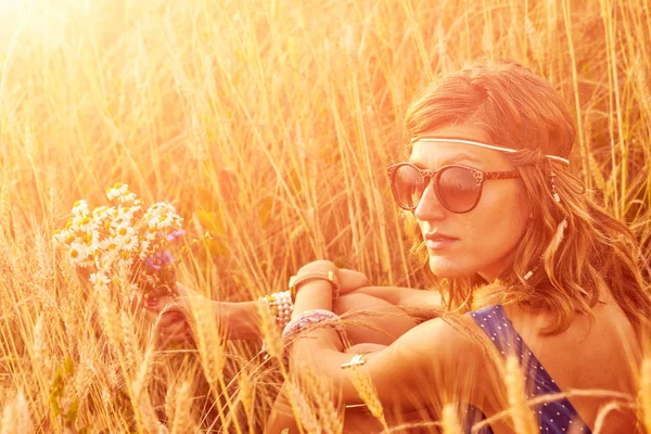 Woman with bouquet of flowers in a wheat field. — Stock Photo, Image