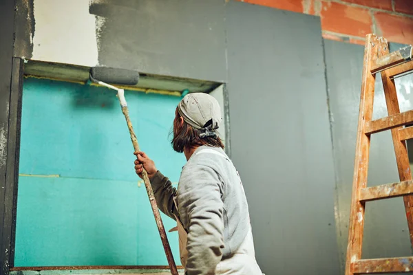 Paredes de pintura pintor com um rolo extensor dentro de casa . — Fotografia de Stock