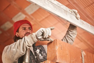 Gerçek inşaat işçisi yeni evin içinde bir duvar yapma.