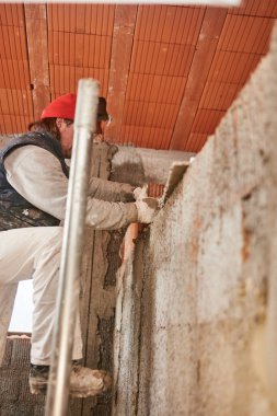 Gerçek inşaat işçisi yeni evin içinde bir duvar yapma.