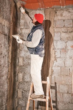 Gerçek inşaat işçisi yeni evin içinde bir duvar yapma.