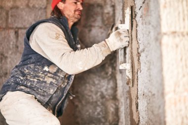 Gerçek inşaat işçisi yeni evin içinde bir duvar yapma.