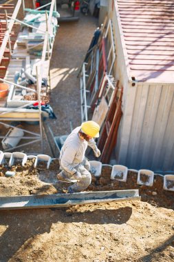 Ağır bir sitede inşaat işçisi sıkı çalışma yapıyor.