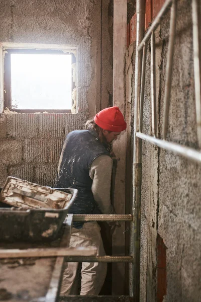 Πραγματικός εργάτης κατασκευών φτιάχνοντας έναν τοίχο μέσα στο νέο σπίτι. — Φωτογραφία Αρχείου