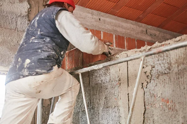 Πραγματικός εργάτης κατασκευών φτιάχνοντας έναν τοίχο μέσα στο νέο σπίτι. — Φωτογραφία Αρχείου