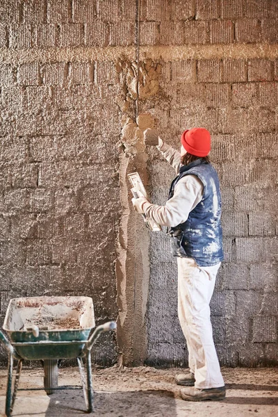 Πραγματικός εργάτης κατασκευών φτιάχνοντας έναν τοίχο μέσα στο νέο σπίτι. — Φωτογραφία Αρχείου