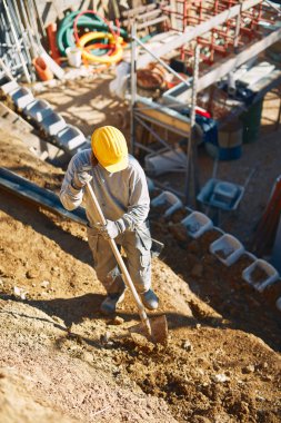 Ağır bir sitede inşaat işçisi sıkı çalışma yapıyor.