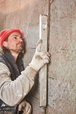 Gerçek inşaat işçisi yeni evin içinde bir duvar yapma.