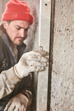 Gerçek inşaat işçisi yeni evin içinde bir duvar yapma.