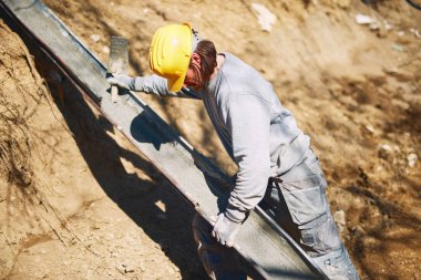 Ağır bir sitede inşaat işçisi sıkı çalışma yapıyor.