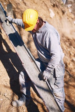 Ağır bir sitede inşaat işçisi sıkı çalışma yapıyor.