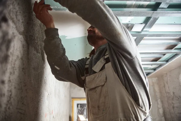 Workman plastering gypsum walls inside the house.