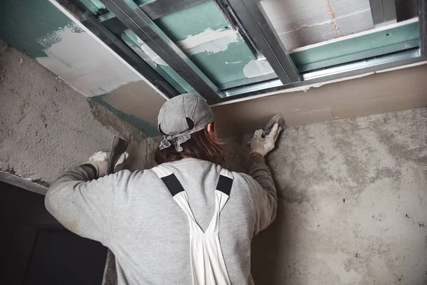 Worksman plastering gypsum walls inside the house.