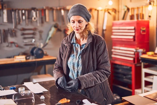 Woman carpenter sanding old window in a retro workshop.