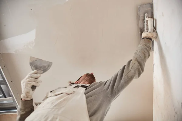 Trabalhador rebocando paredes de gesso dentro da casa . — Fotografia de Stock