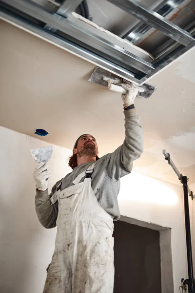 Worksman plastering gypsum walls inside the house. Stock Picture