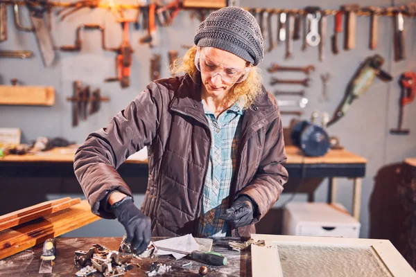 Woman carpenter sanding old window in a retro workshop. — Stock Photo, Image