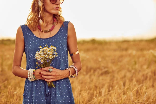 Žena s kyticí květinami v pšeničném poli. — Stock fotografie