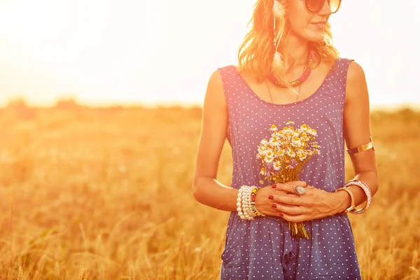 Žena s kyticí květinami v pšeničném poli. — Stock fotografie