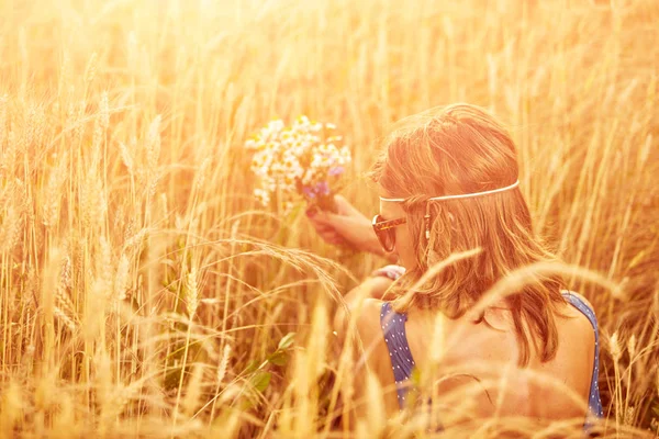 Woman with bouquet of flowers in a wheat field. — Stock Photo, Image