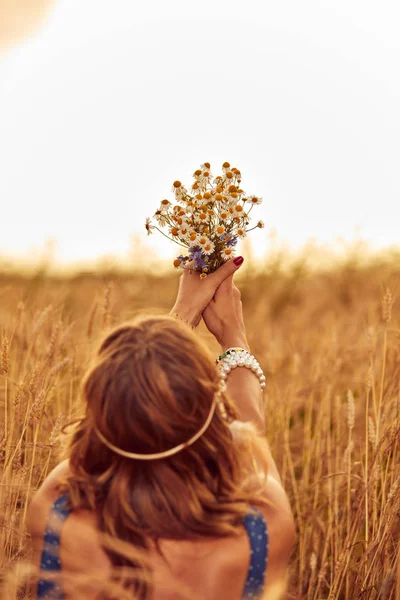 Woman with bouquet of flowers in a wheat field. — Stock Photo, Image