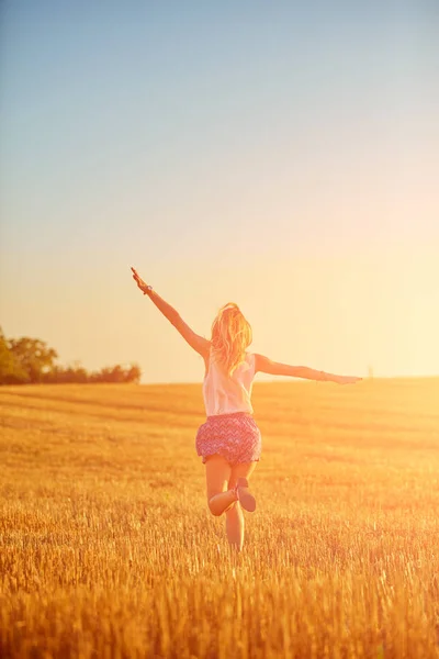 Junge Frau springt und rennt in einem Weizenfeld. — Stockfoto