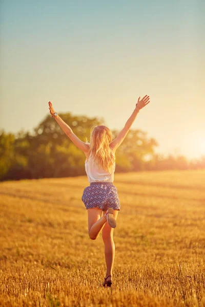 Junge Frau springt und rennt in einem Weizenfeld. — Stockfoto