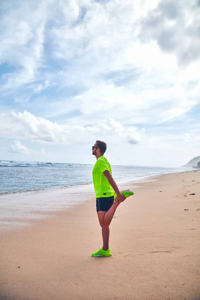 Deportista estirándose en una playa de arena tropical . — Foto de Stock