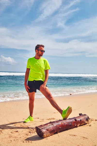 Deportista estirándose en una playa de arena tropical . —  Fotos de Stock