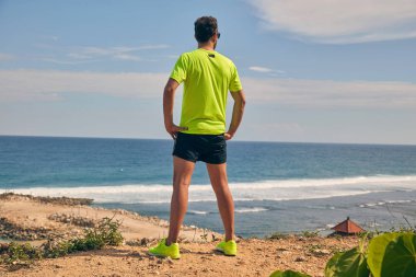 Okyanusa yakın tropik egzotik bir kayalıkta sporcu.